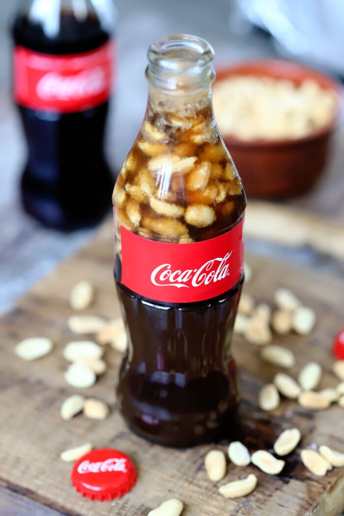 Peanuts and Coke on a wooden board.