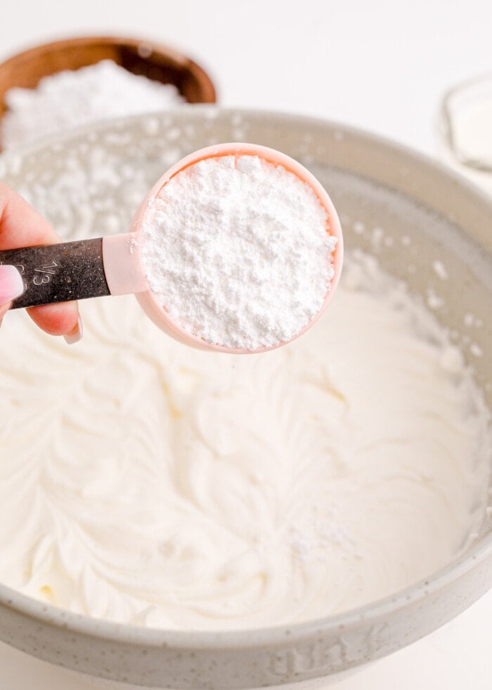 adding powdered sugar to the beaten heavy cream