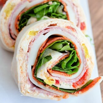 Three Italian pinwheel sandwiches lined up on a white platter.