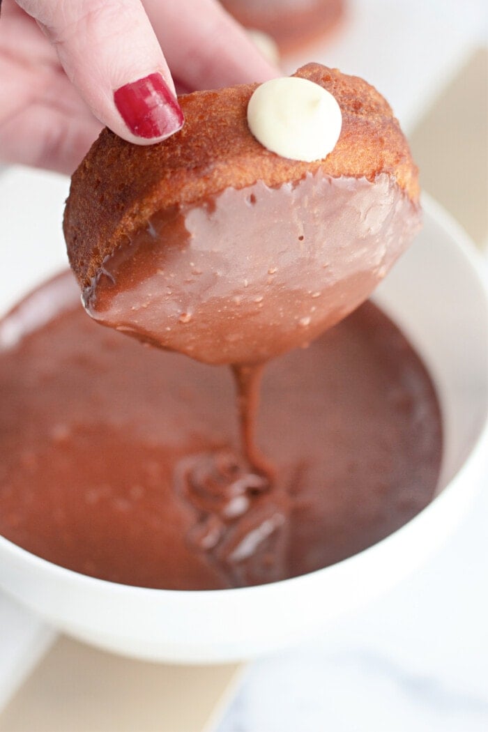 dipping the donut into chocolate icing