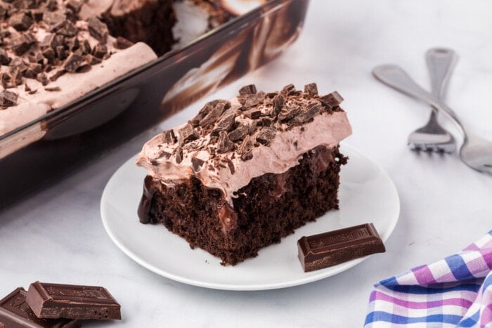 Chocolate Poke Cake with a piece of chocolate on the side.