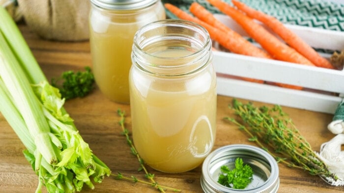 Turkey Stock in a jar with vegetables around it.