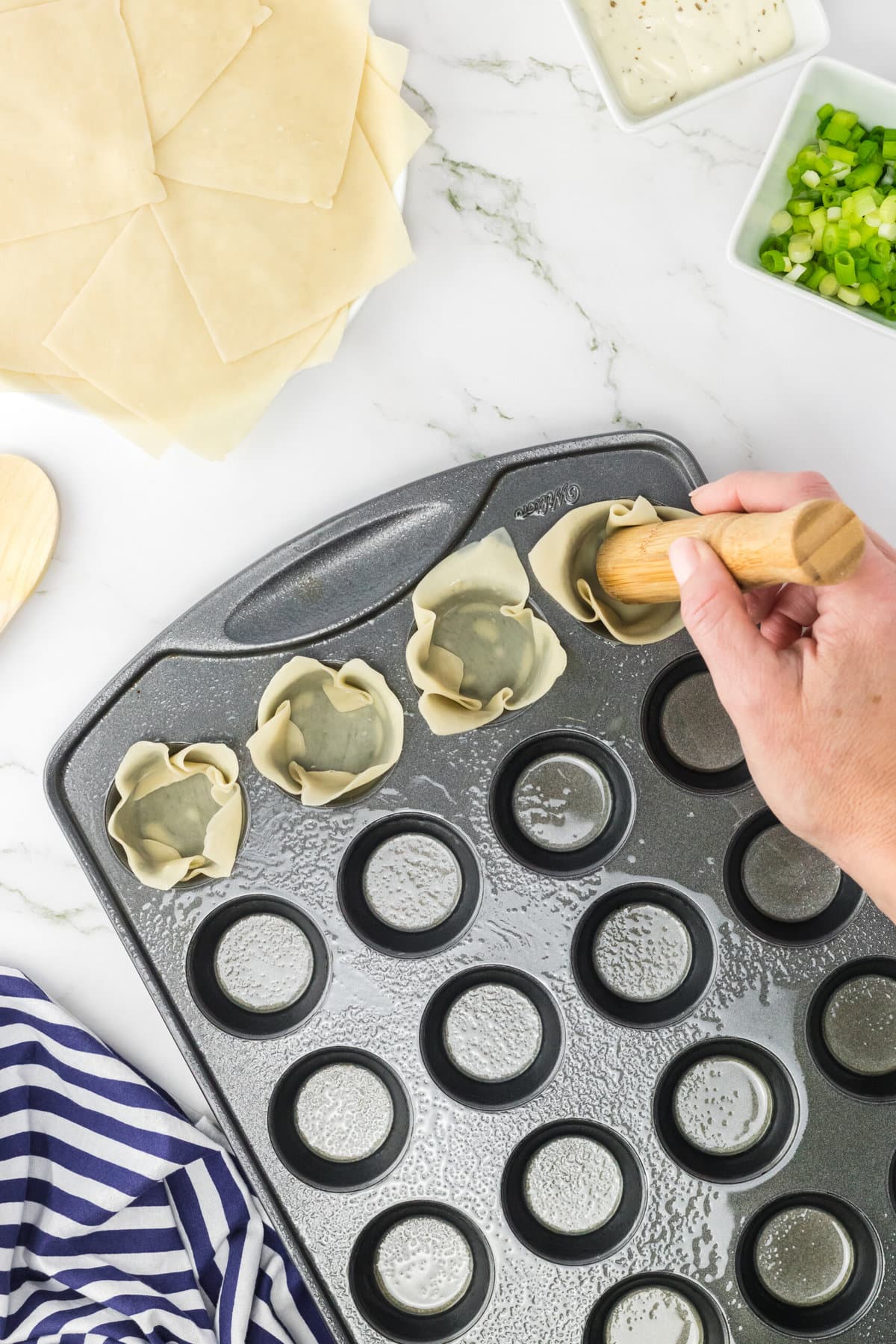 Putting the wrappers in the muffin tin.