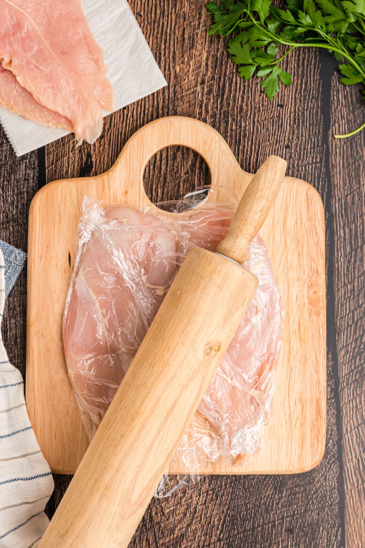 A rolling pin flattening chicken breasts