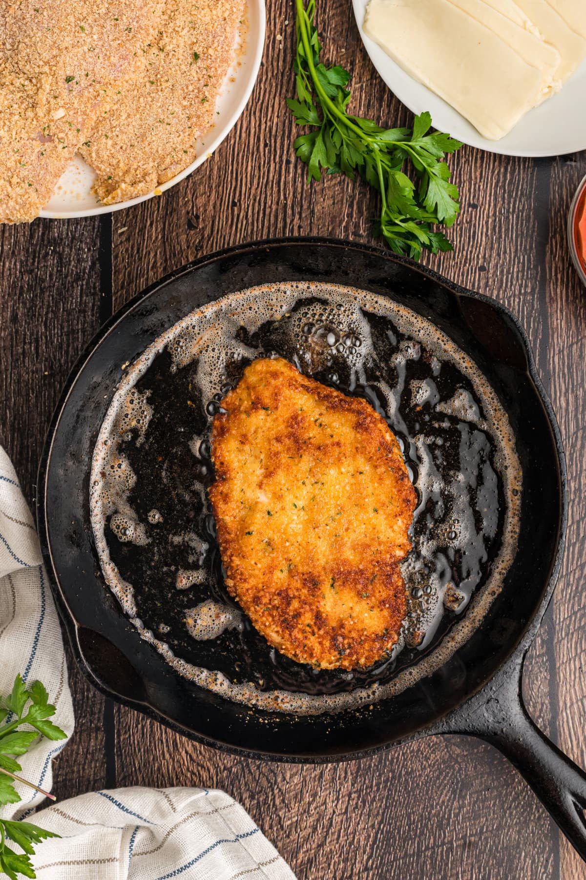 A chicken breast frying in a skillet
