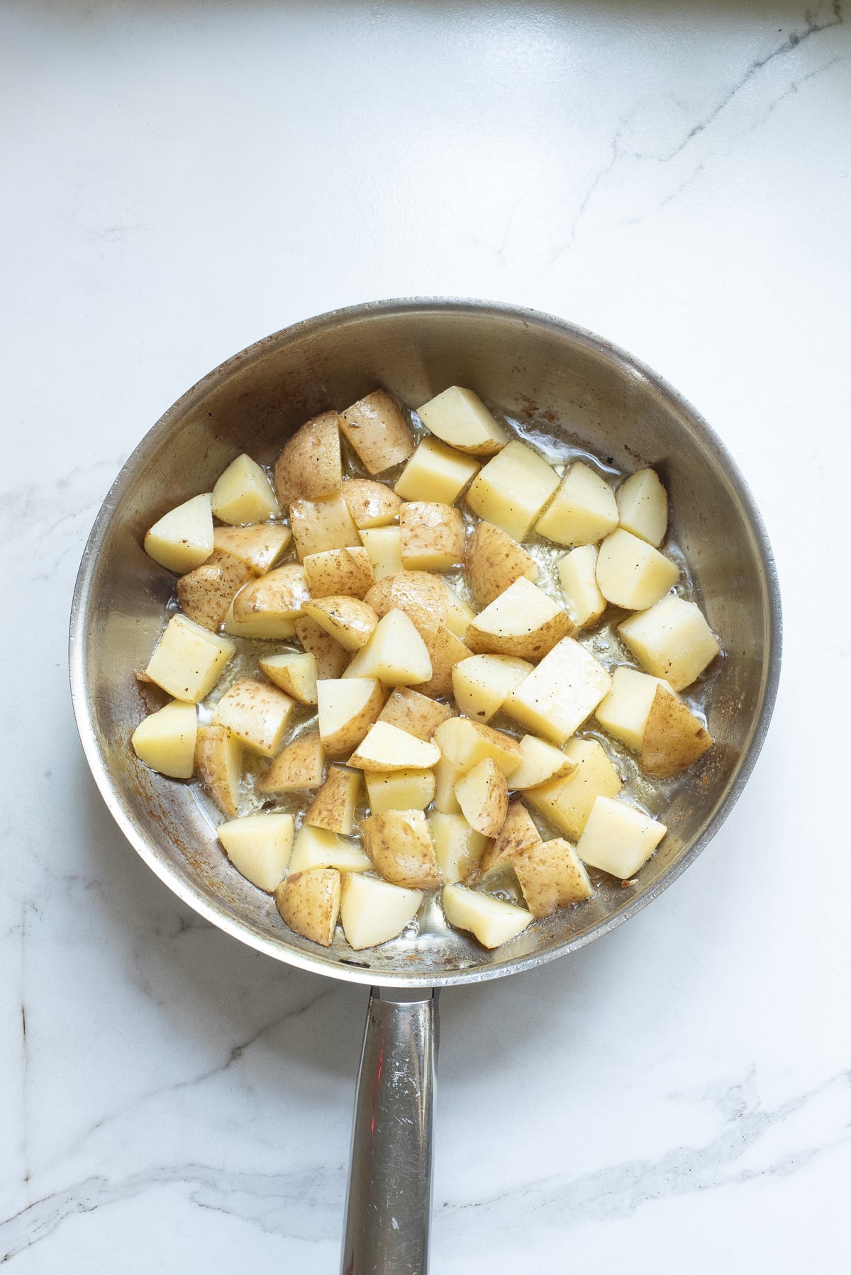Chunks of potato in a metal skillet
