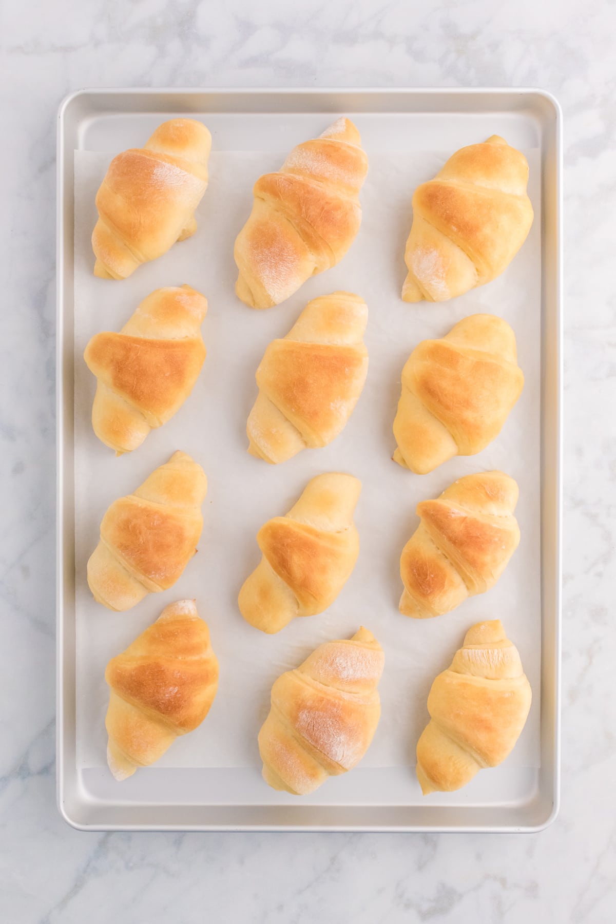 Freshly baked crescent rolls on a baking sheet