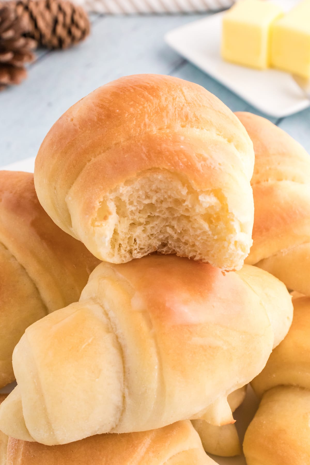 A pile of crescent rolls, the top one with a bite missing