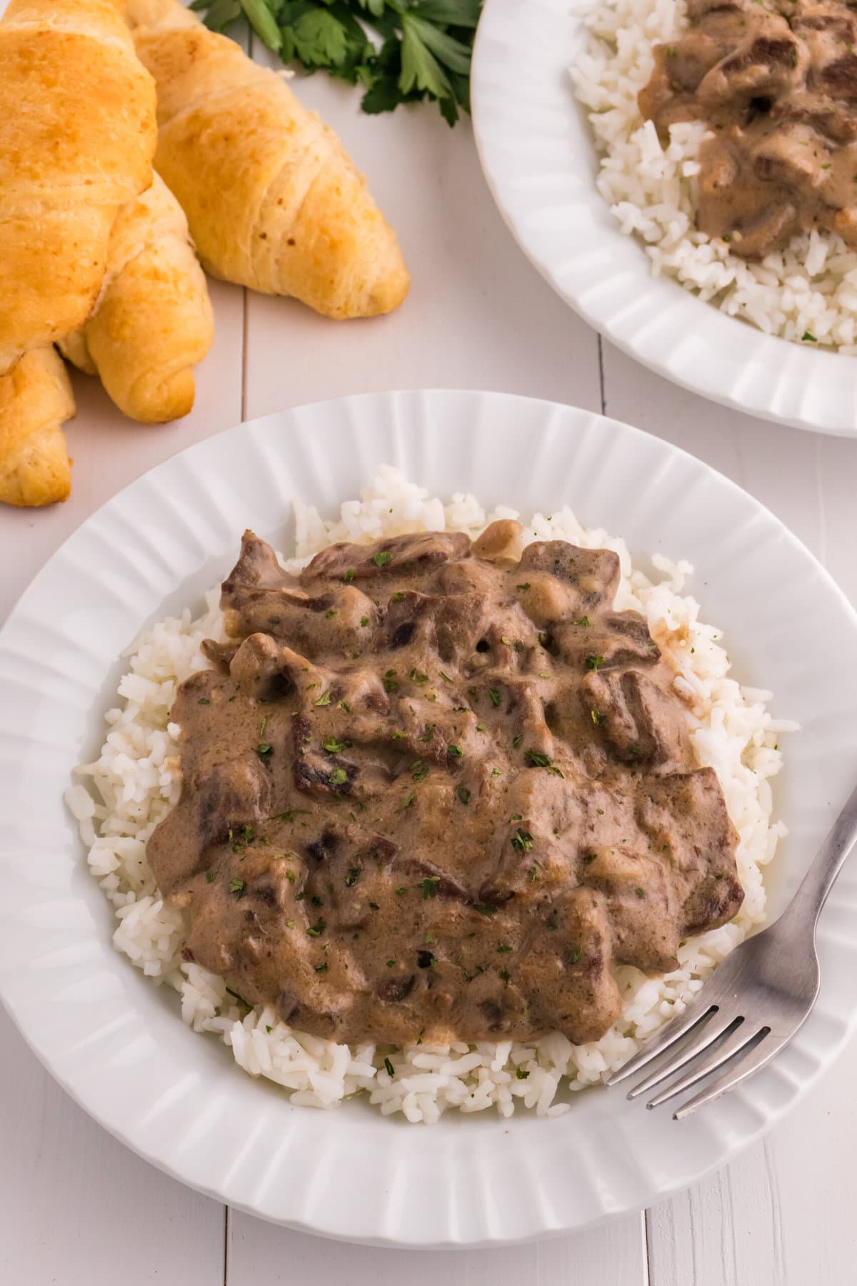 Beef Tips and Rice with croissants on the side.