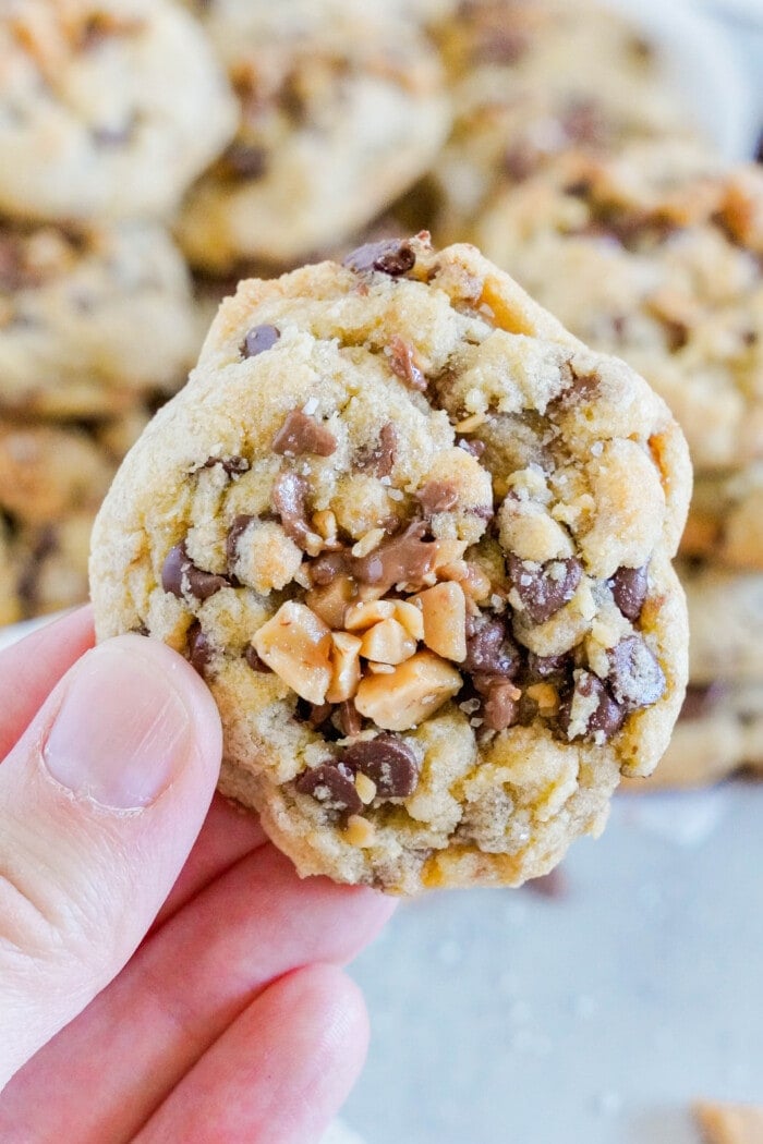 A hand holding one of the Toffee Chocolate Chip Cookies.
