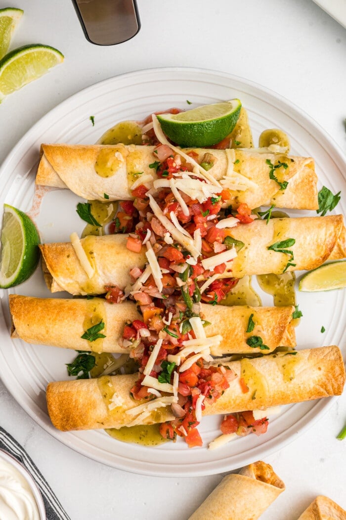 Air Fryer Chicken Taquitos topped with garnishes.