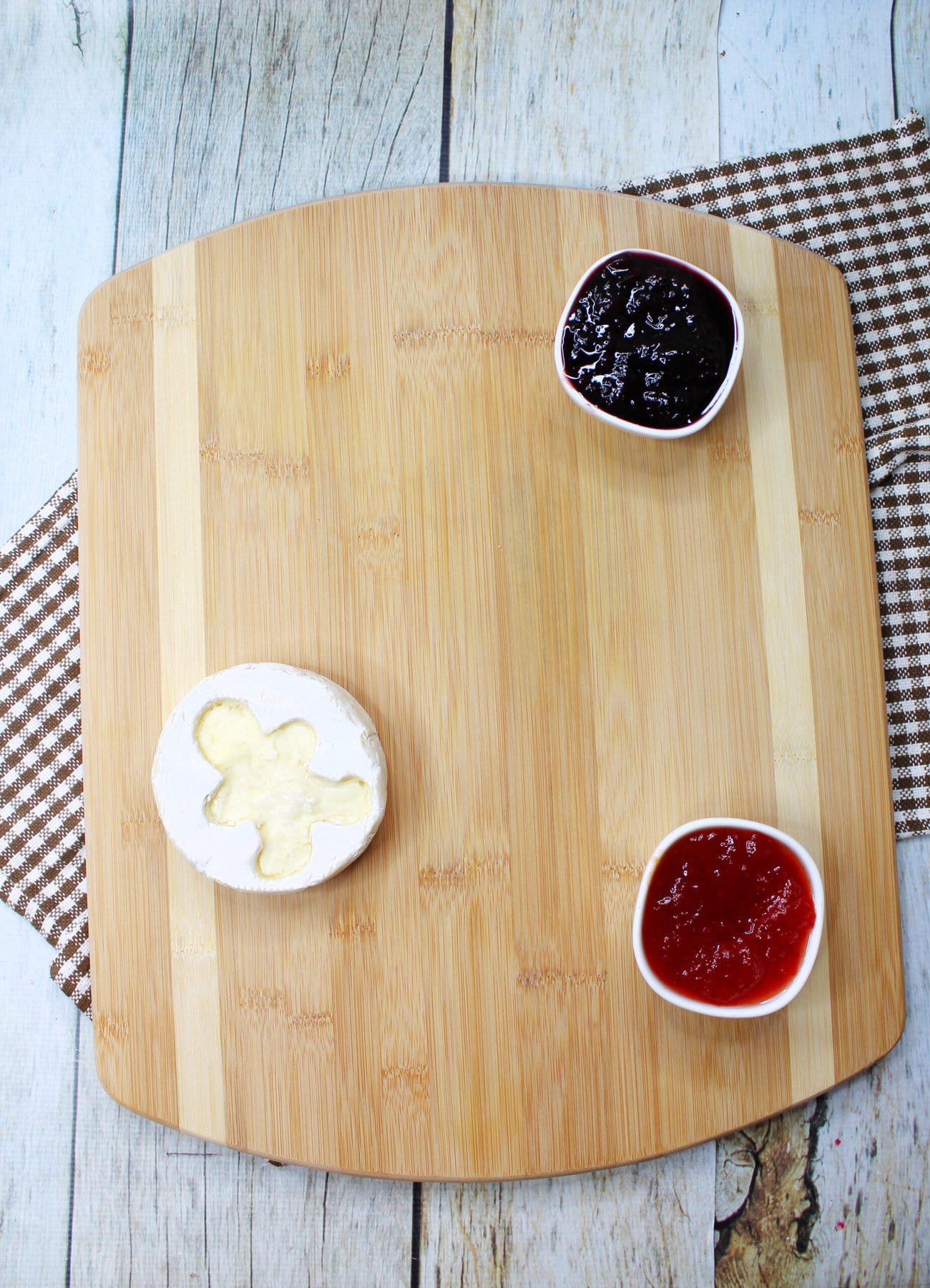 Adding the brie, jam, and jelly onto the board.