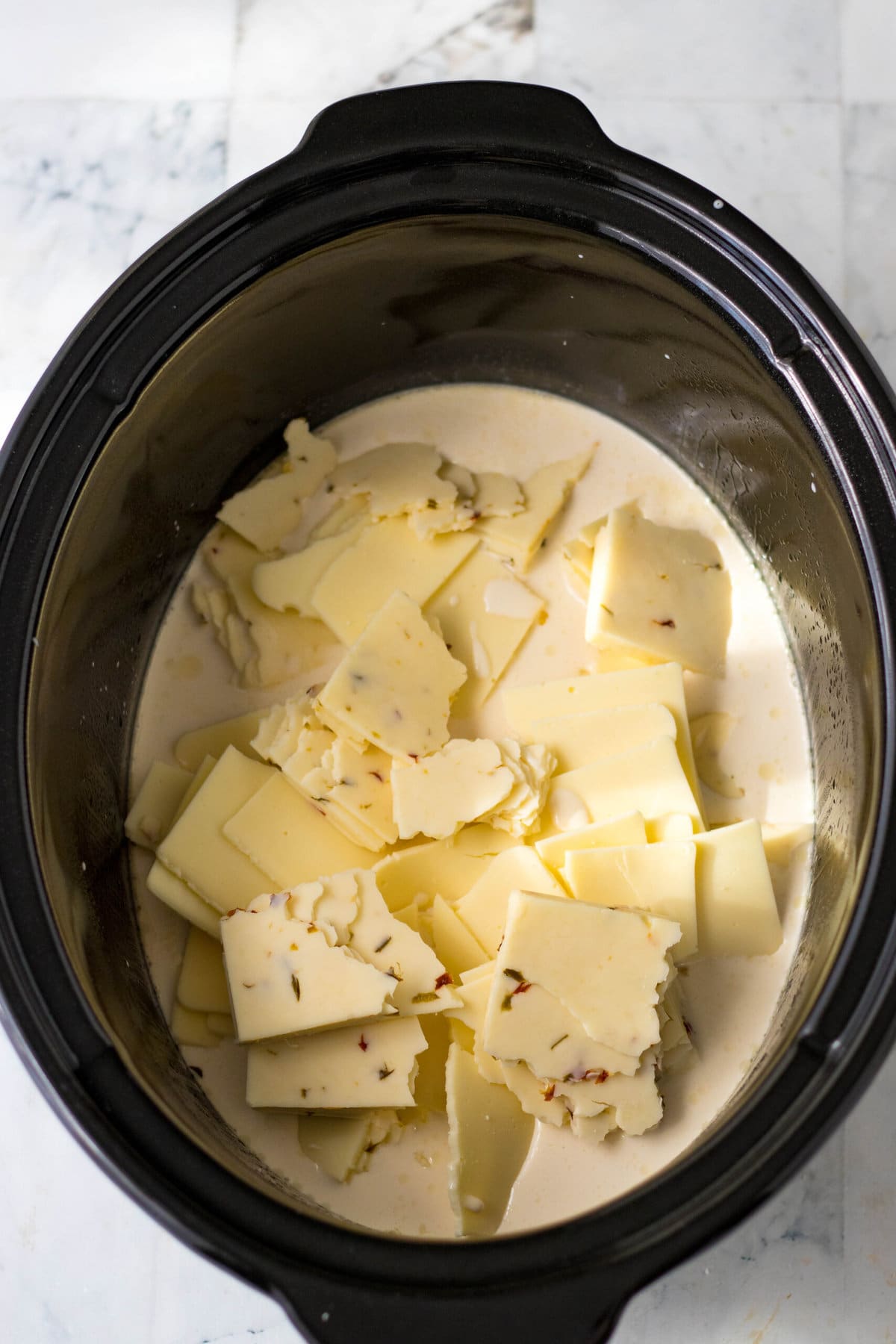 Breaking up the cheese and adding into the slow cooker.