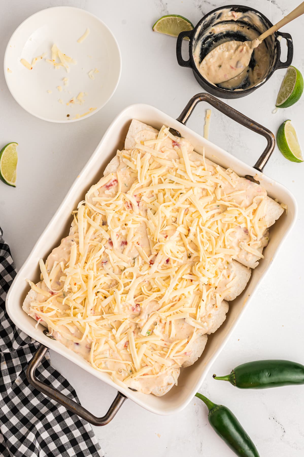 Enchiladas topped with queso blanco and shredded cheese in a baking dish