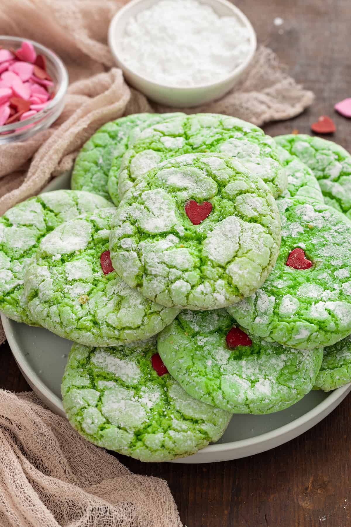 These Grinch Cookies are a fun and festive holiday treat, with the signature bright green color and red candy heart. A plate of Grinch cookies