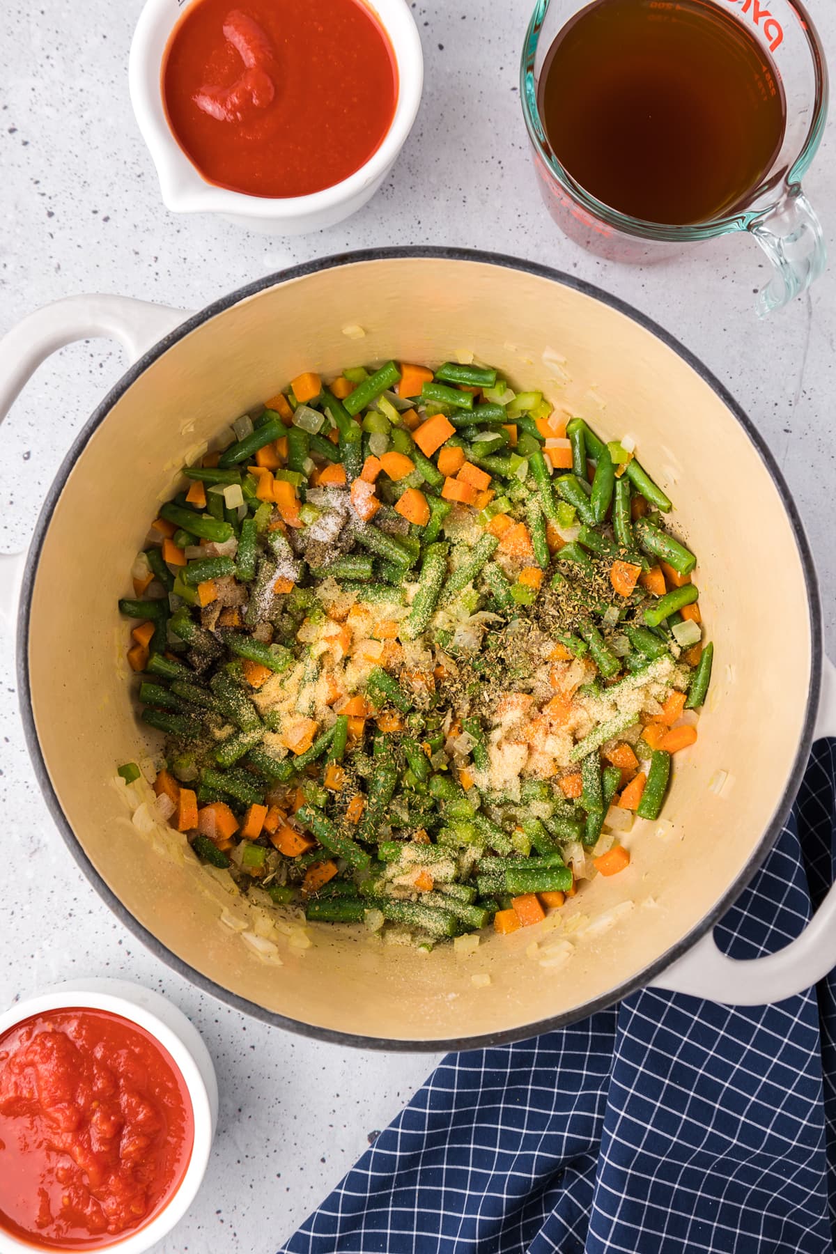 Green beans, carrots, onion, celery, and seasonings in the bottom of a pot