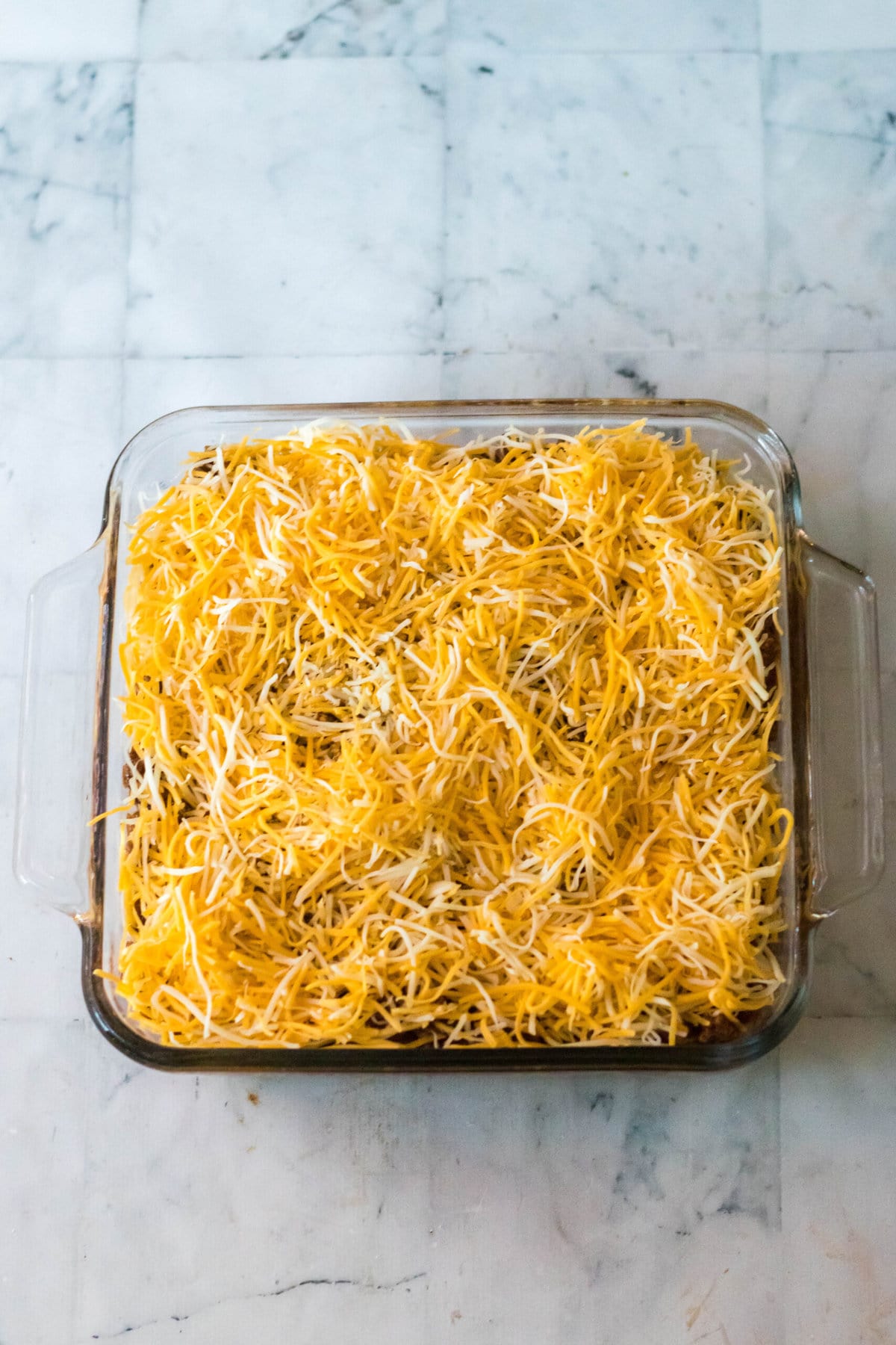 Adding a layer of shredded cheese.