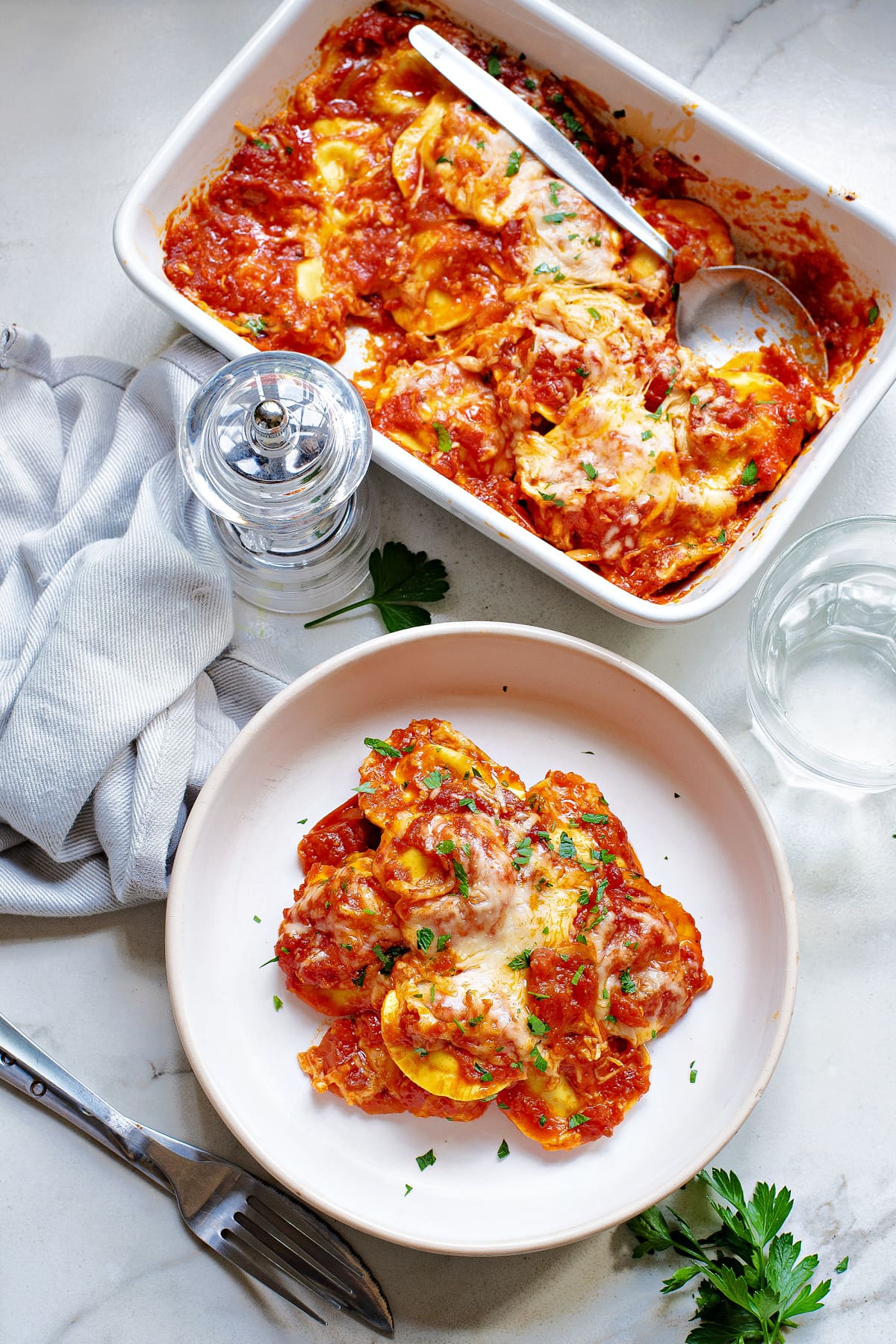 baked ravioli served in white dish with parsley and in white baking dish