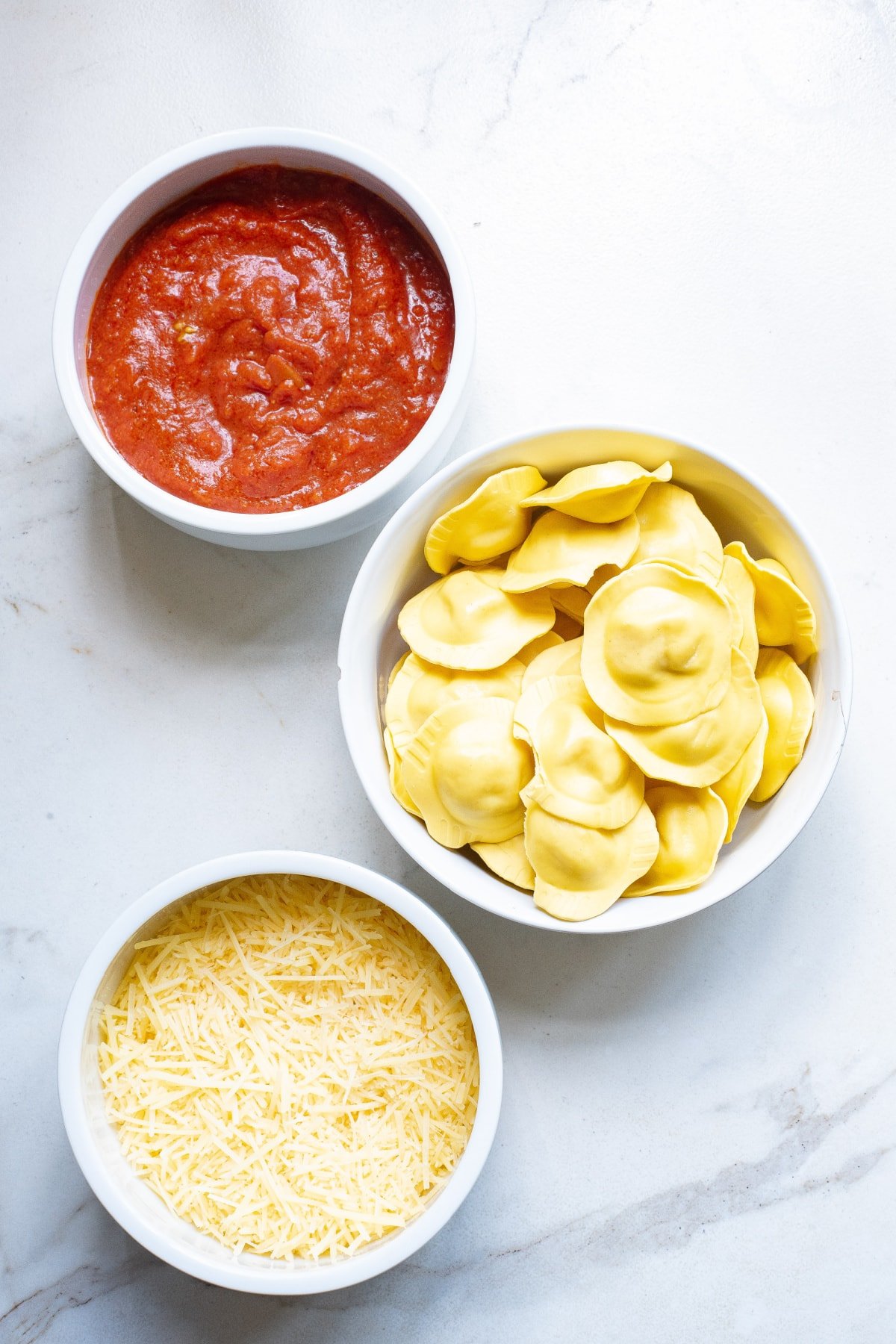 ingredients needed for baked ravioli in white bowls