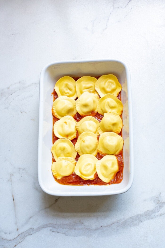 ravioli with sauce for baked ravioli in white rectangle baking dish