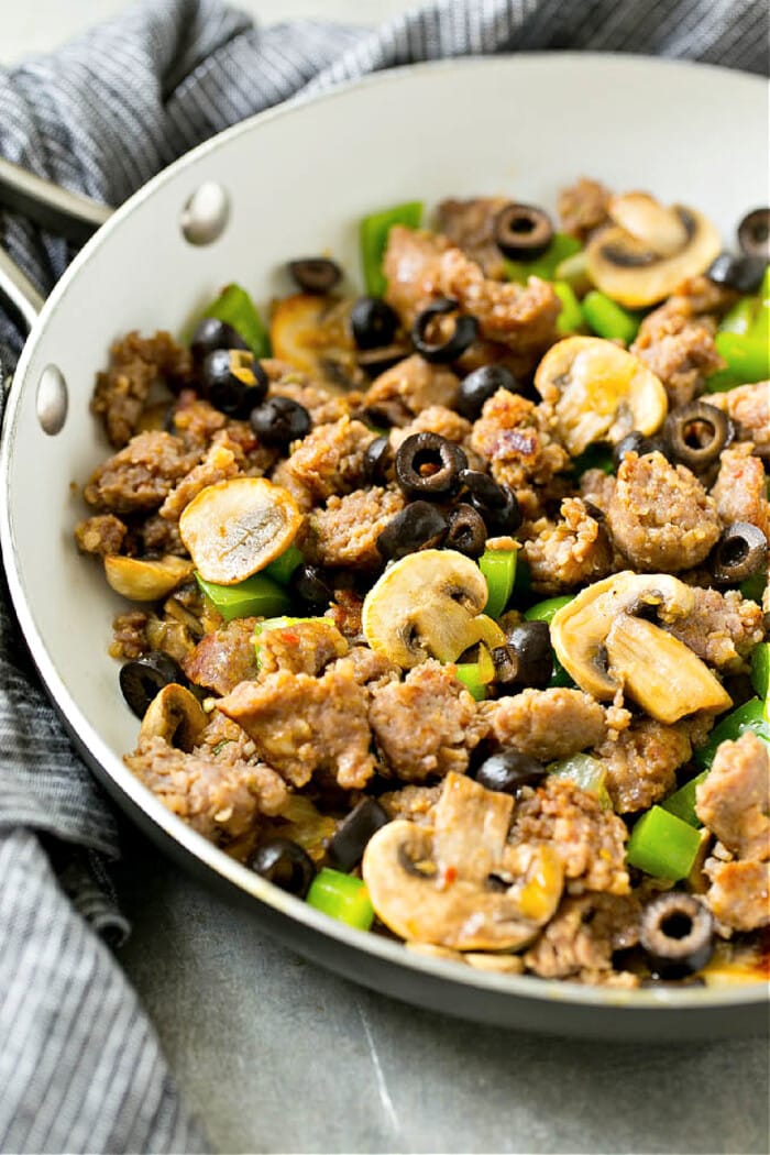skillet with onion, mushrooms, sausage, pepper, olives