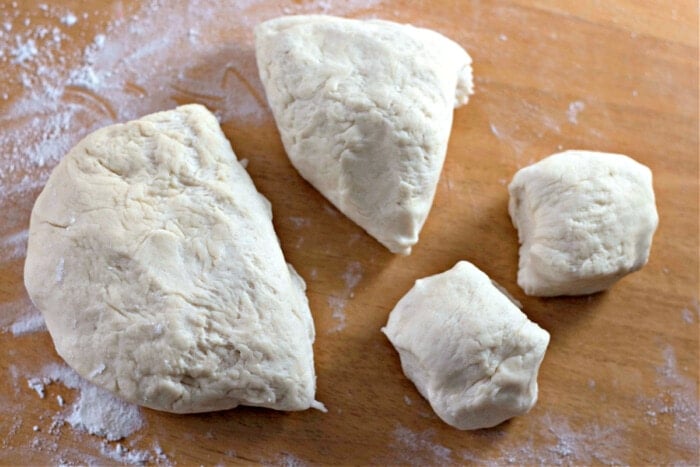 tortilla dough cut into pieces with flour on board