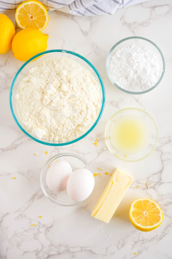 ingredients needed for lemon crinkle cookies in clear glass bowls