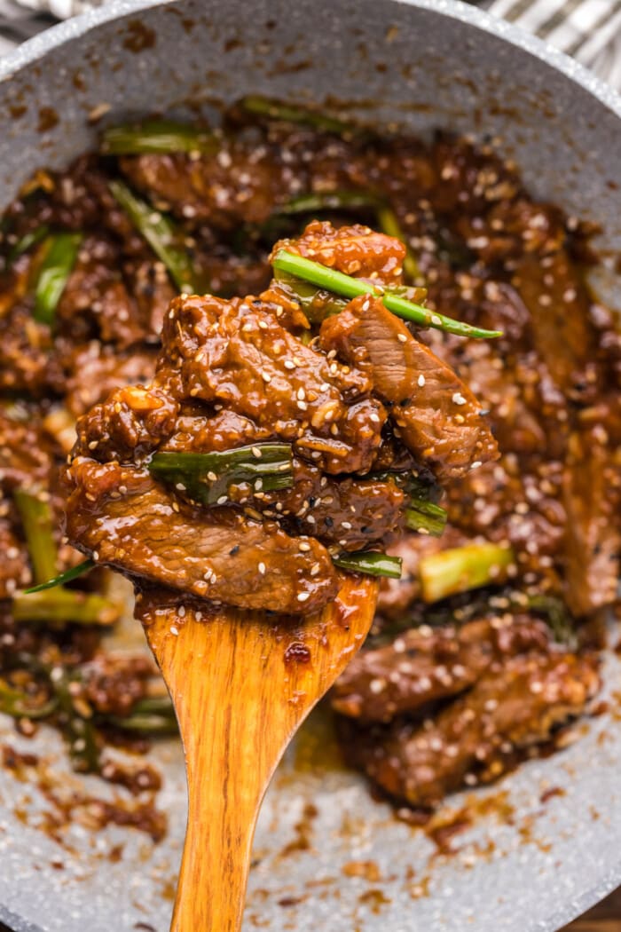 beef with green onions and sesame seeds in gray wok pan