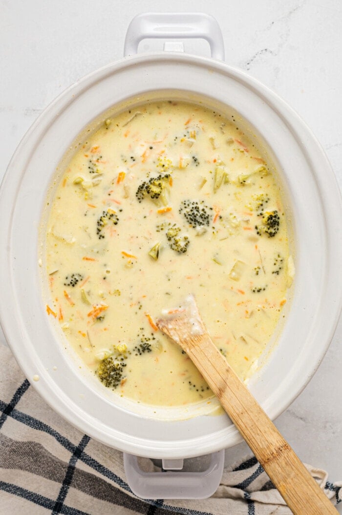 slow cooker broccoli cheddar soup with wooden spoon and napkin