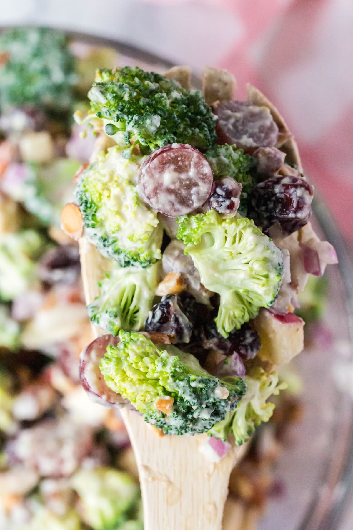 A close up of healthy broccoli salad on a wooden spoon