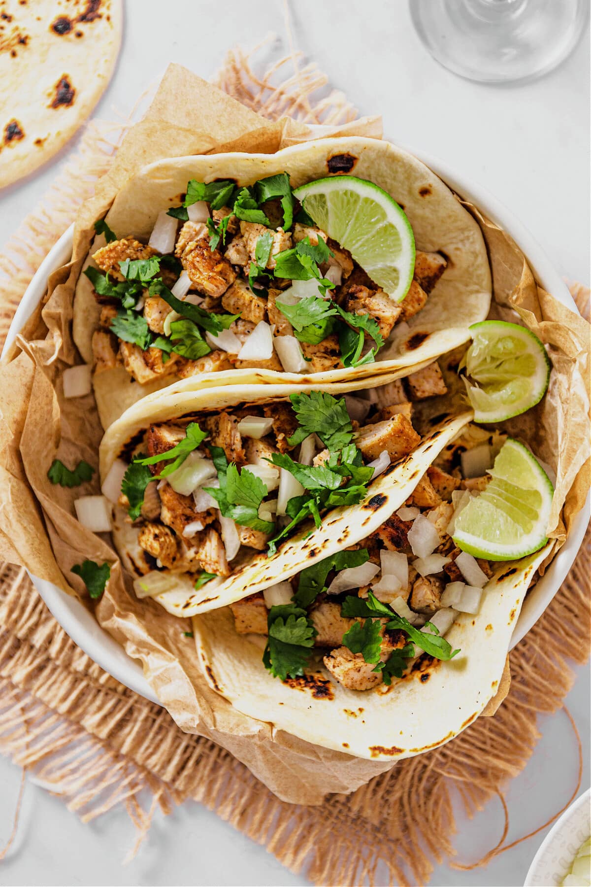 bowl with chicken street tacos topped with onions, cilantro and lime wedges