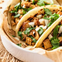 white bowl with chicken tacos topped with onions and cilantro