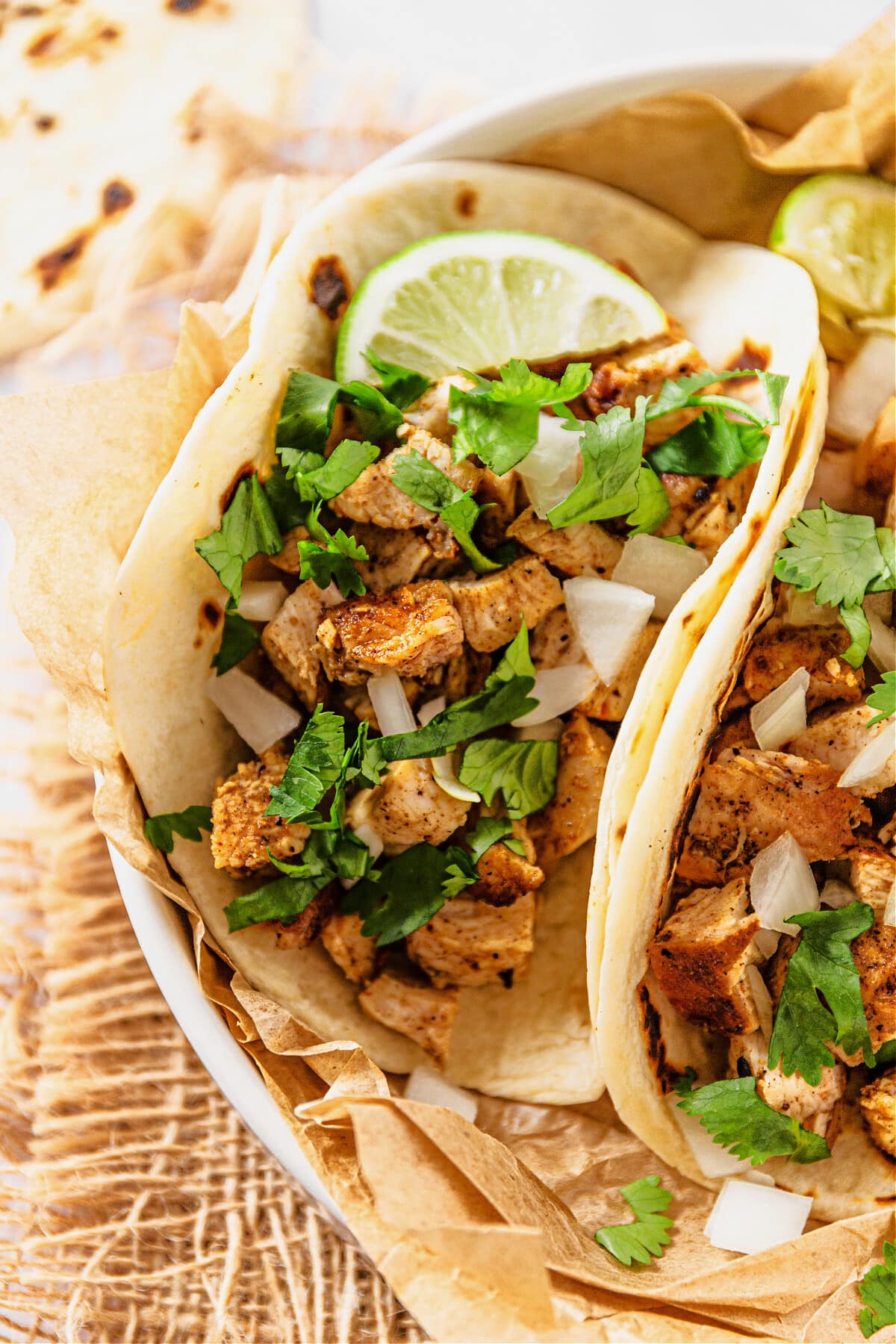taco with chicken and topped with onions, cilantro and limes