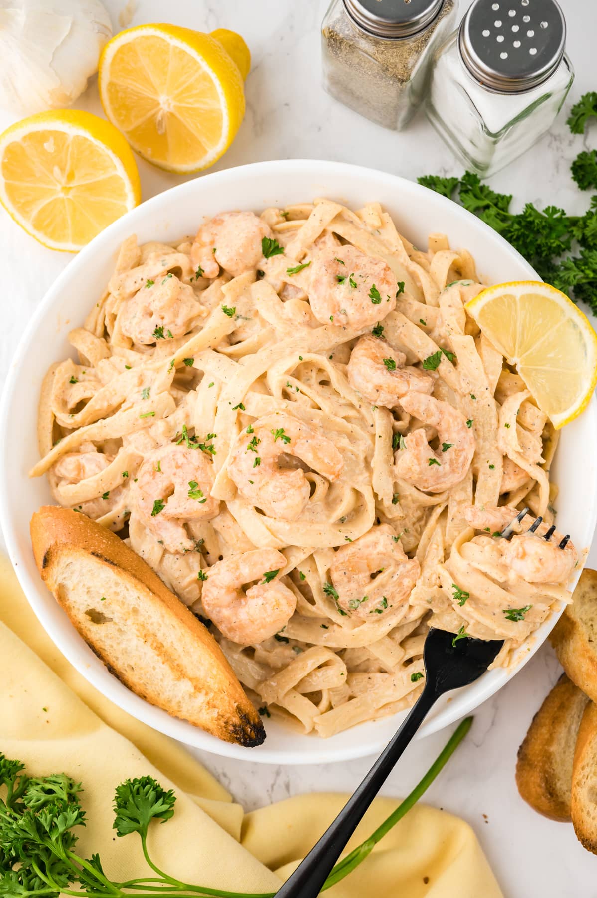 Overhead view of a bowl of creamy shrimp pasta with a piece of garlic bread