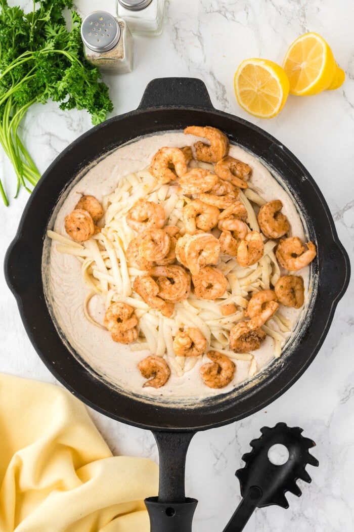 Creamy pasta sauce, fettucine noodles, and shrimp in a skillet