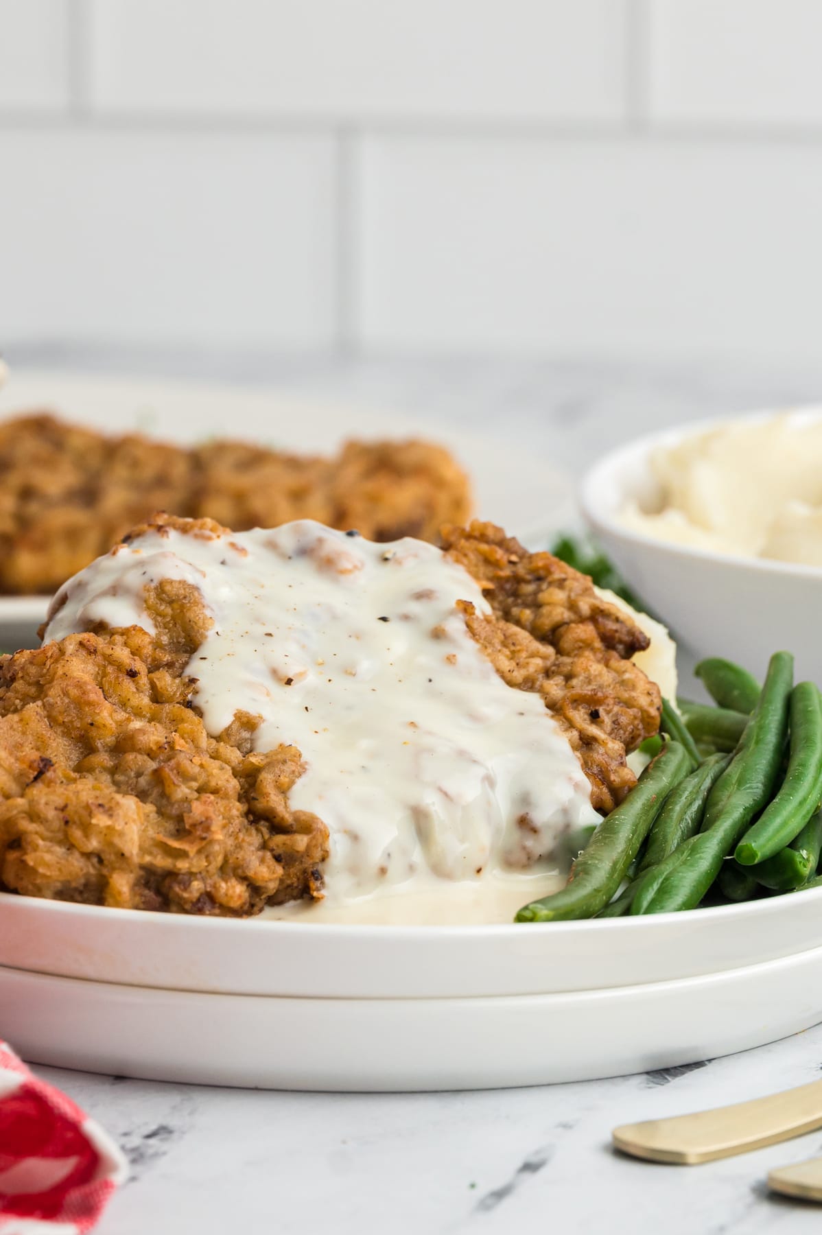 Chicken fried steak with gravy on a plate with green beans