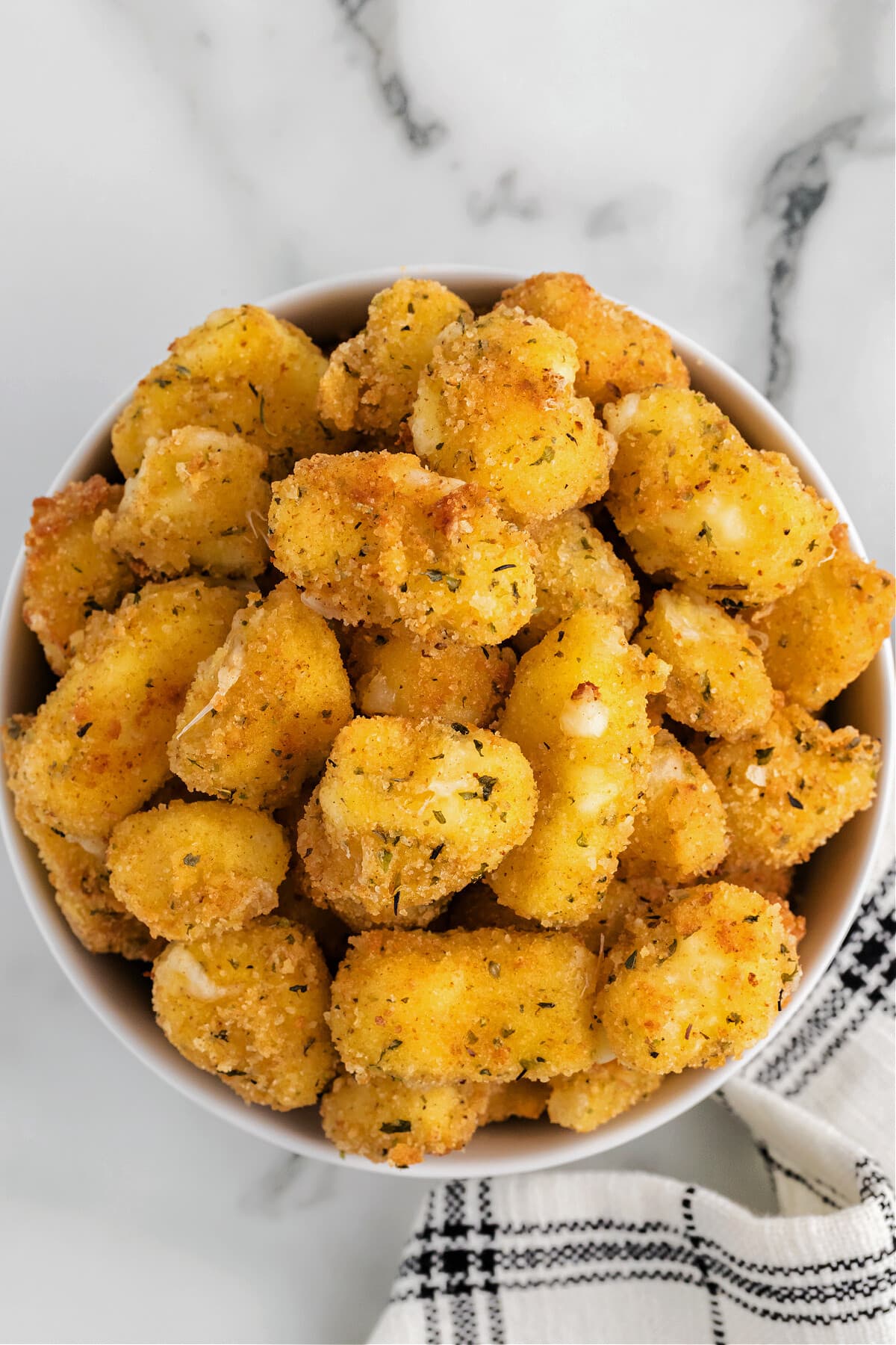 homemade cheese curds in white bowl with black and white napkin