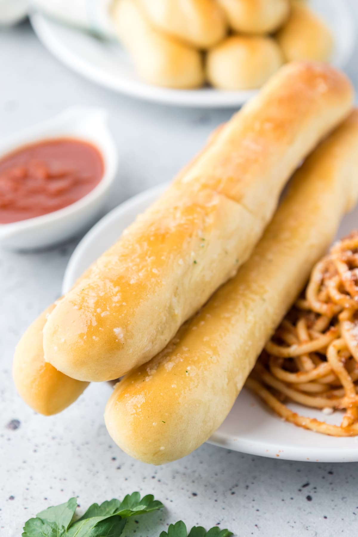 Copycat olive garden breadsticks on a plate with spaghetti
