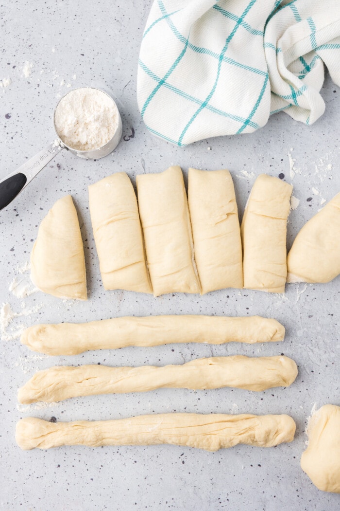 Dough that's been cut into pieces and some rolled into breadsticks