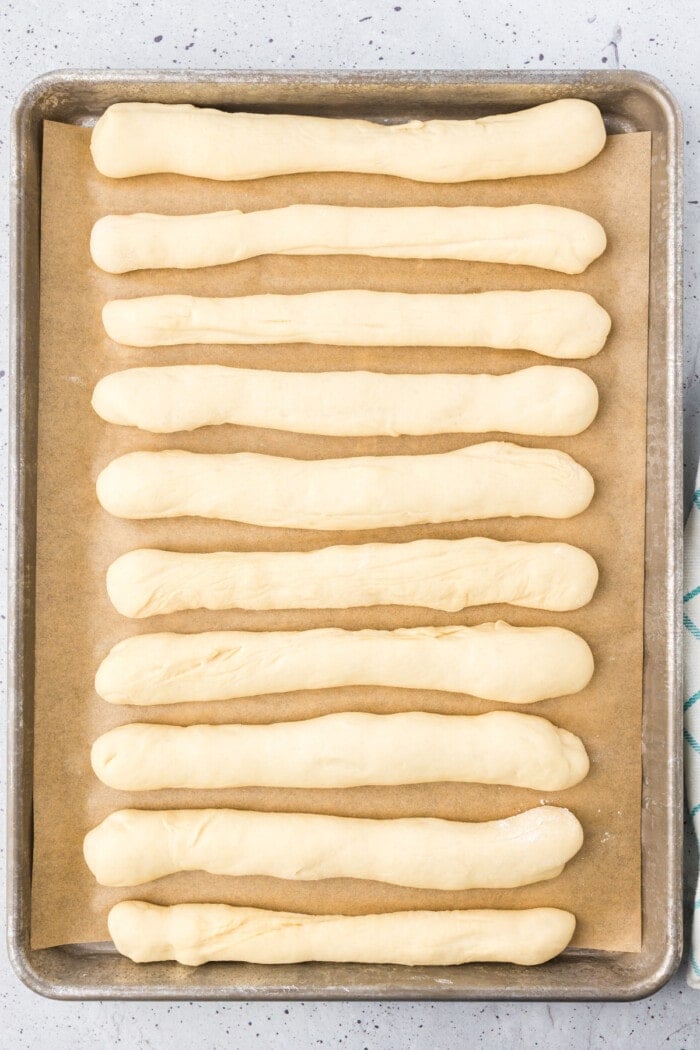 Dough shaped into breadsticks on a baking sheet
