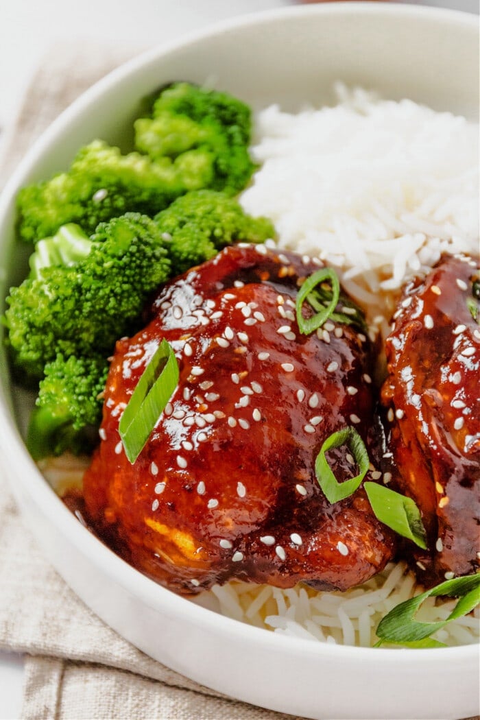 honey garlic chicken thighs in white bowl with broccoli and white rice