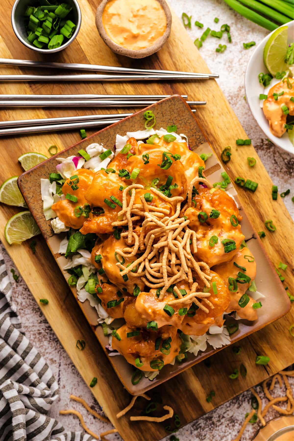 dynamite shrimp on wood platter with green onions and chow mein noodles