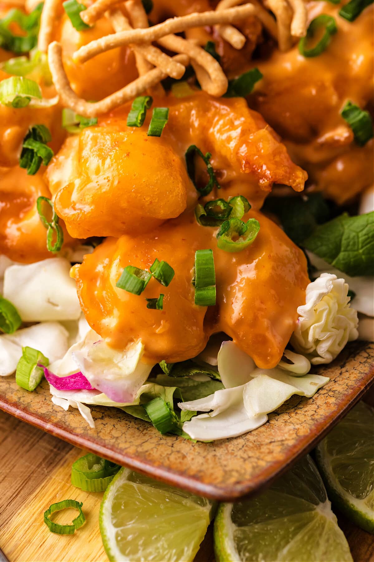 dynamite shrimp on wood platter with cabbage, green onions and chow mein noodles