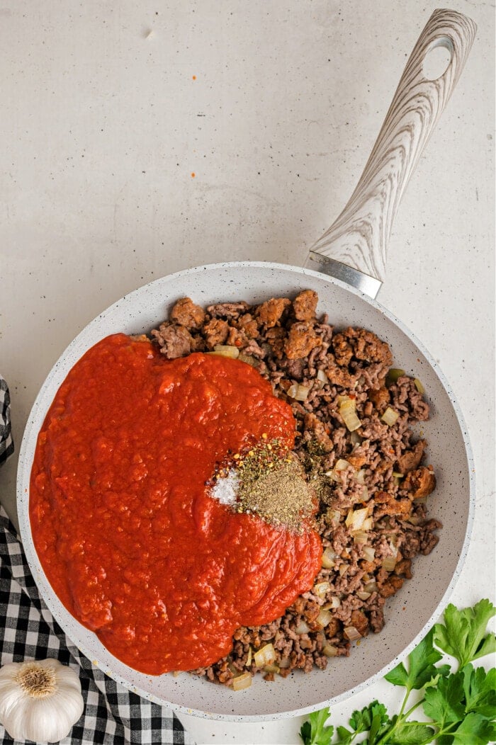 cooked ground beef and red sauce with spices in skillet