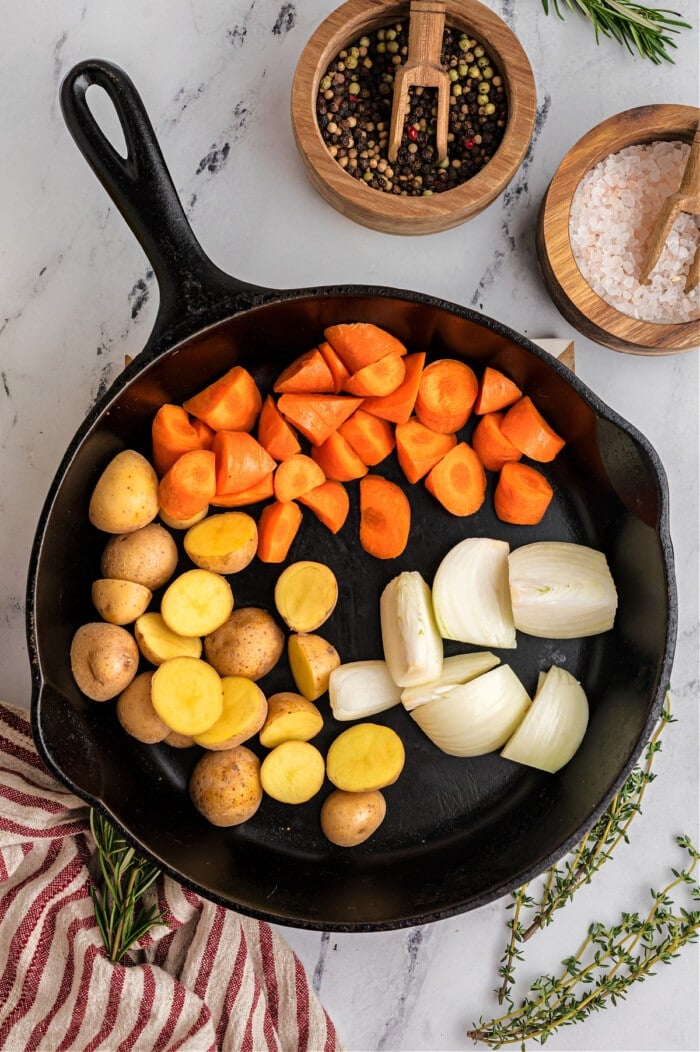 carrots, onions, and potatoes in cast iron skillet