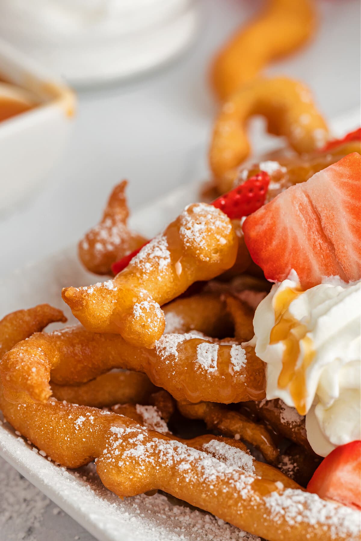 funnel cake fries with powdered sugar, whip cream and strawberries
