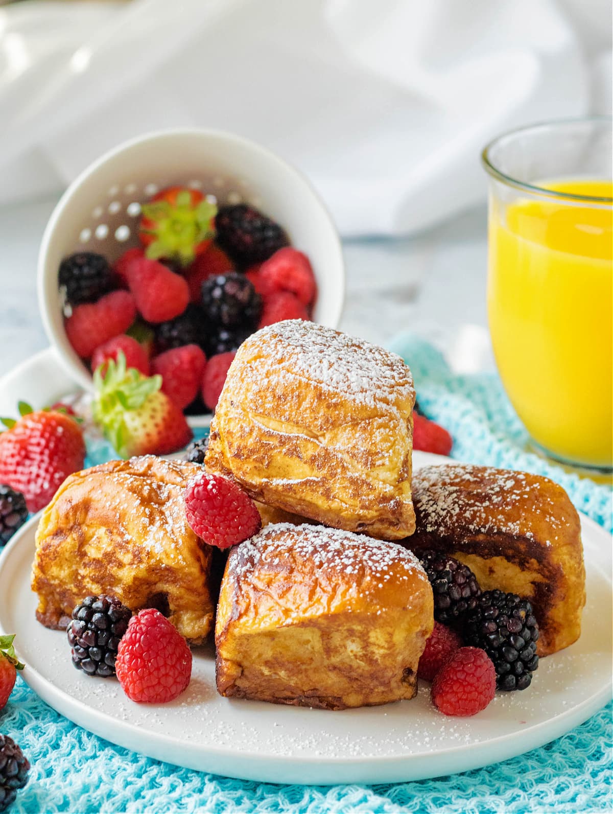 hawaiian roll french toast on white plate with fruit and powdered sugar