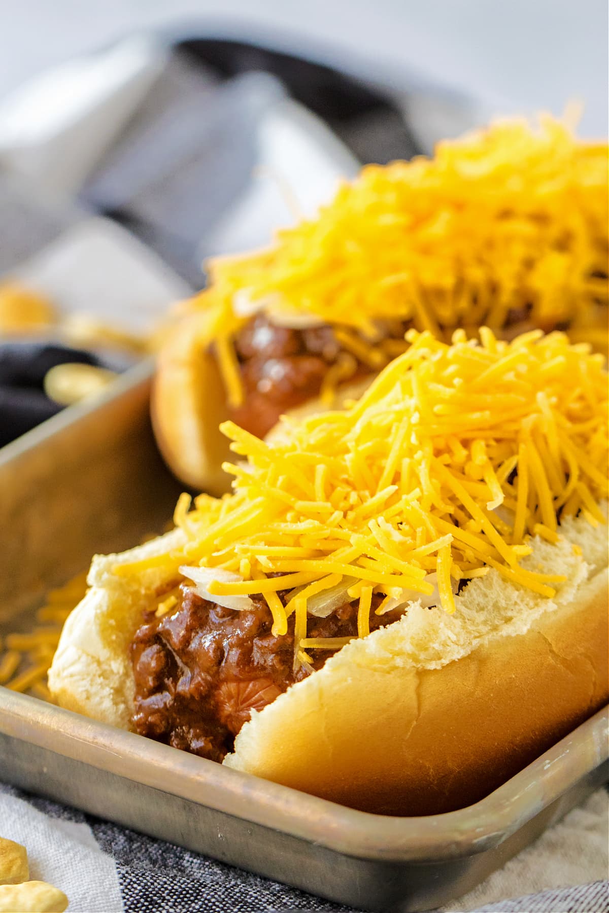 chili on top of hot dogs with onions and cheese