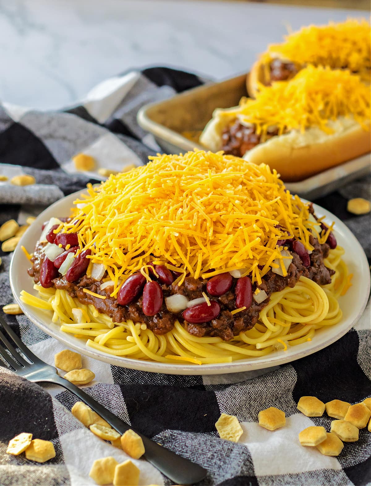 chili on top of spaghetti noodles with beans, onions and cheese on white plate