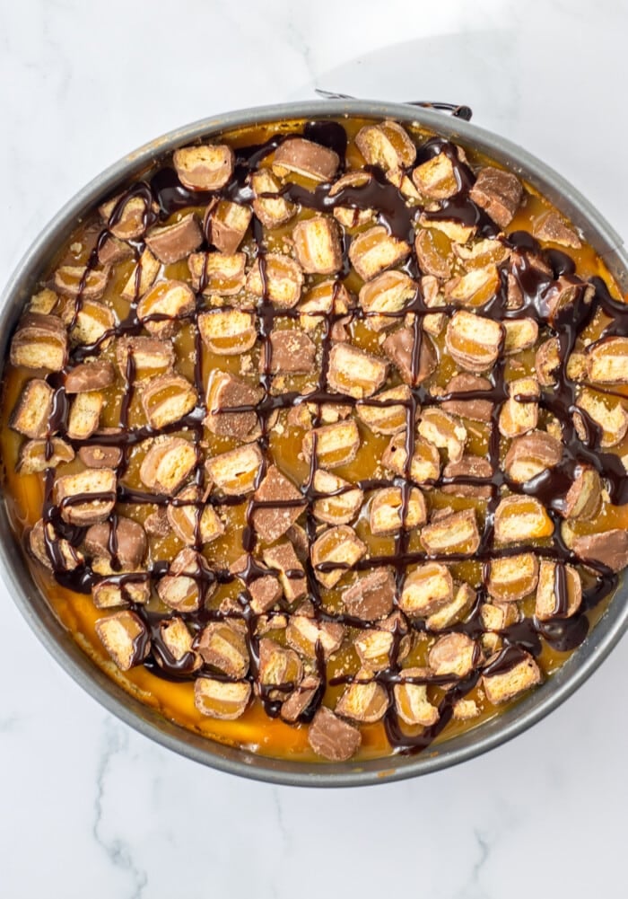 Adding the toppings onto the Twix Cheesecake.